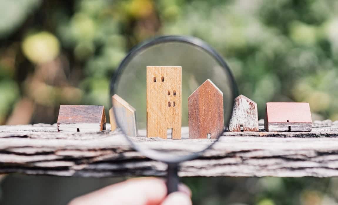 Photo d'une personne tenant une loupe et regardant des biens immobilier en bois