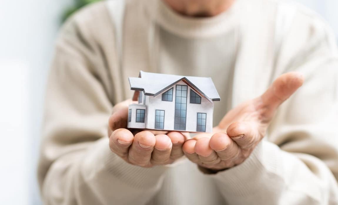 Une image d'une vieille personne tenant une maison